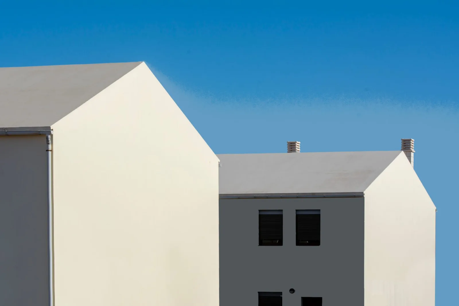Two pale house gables against a clear blue sky.