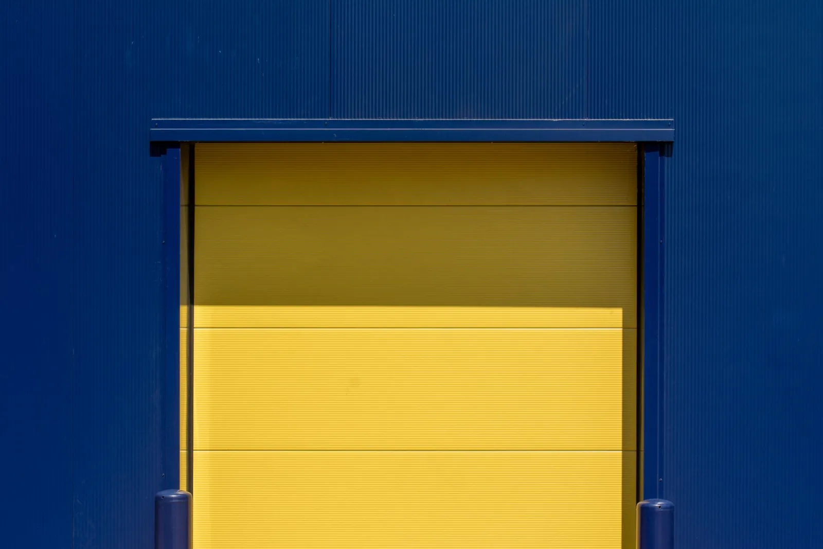 A yellow loading dock door set into a blue wall.
