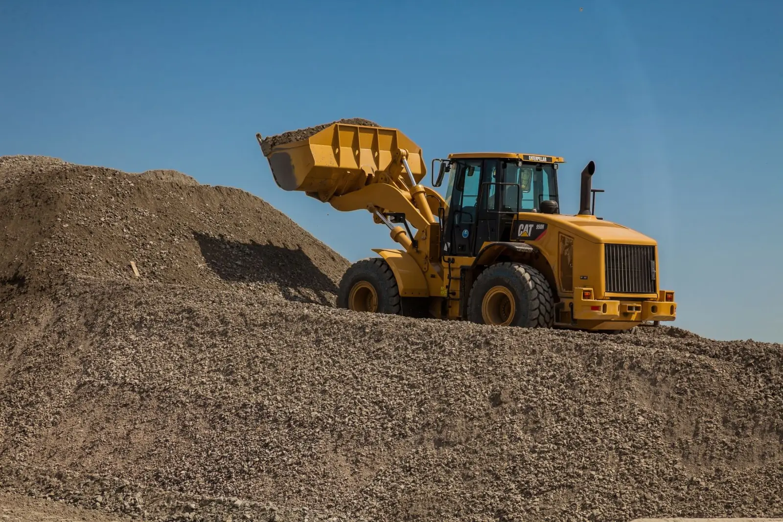 A wheel loader working an aggregate pile under overcast light.